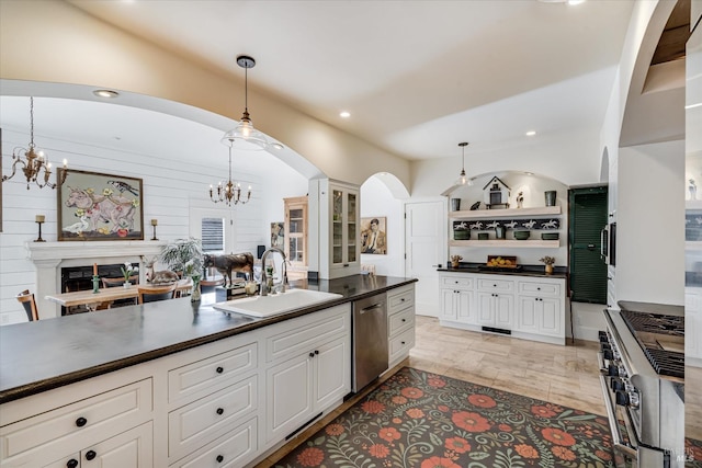 kitchen with dark countertops, hanging light fixtures, an inviting chandelier, stainless steel appliances, and a sink