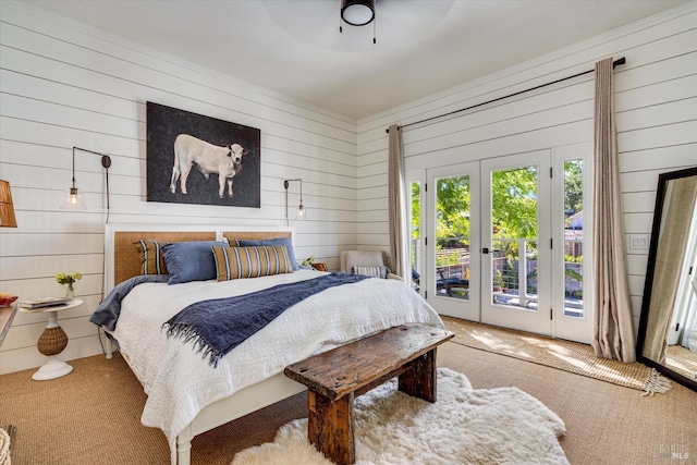 carpeted bedroom with wooden walls, ceiling fan, and access to outside