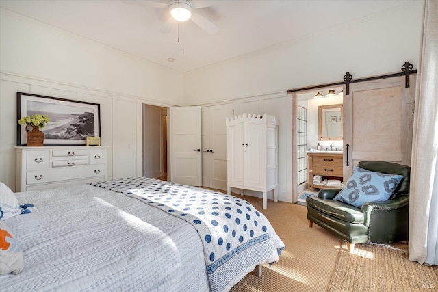 carpeted bedroom featuring a sink, a barn door, and a closet