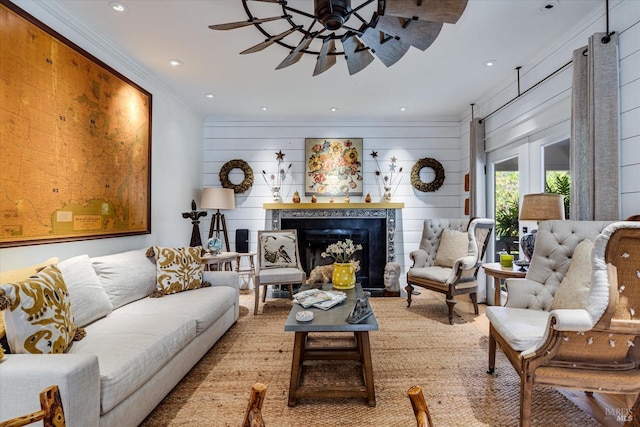 living room with a premium fireplace, ceiling fan, ornamental molding, and wood walls