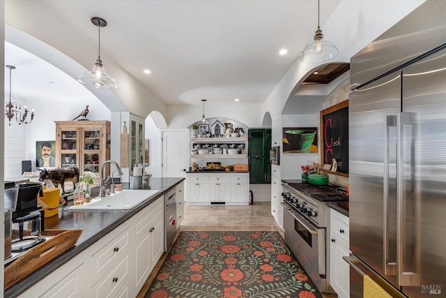 kitchen featuring dark countertops, a sink, high quality appliances, and pendant lighting