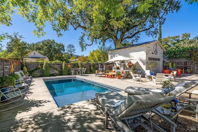 view of swimming pool with a fenced backyard, an outdoor structure, a fenced in pool, and a patio