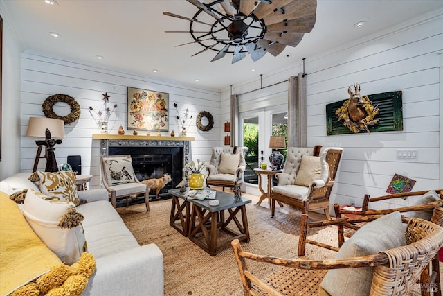 living room with a premium fireplace, french doors, wood walls, and ornamental molding