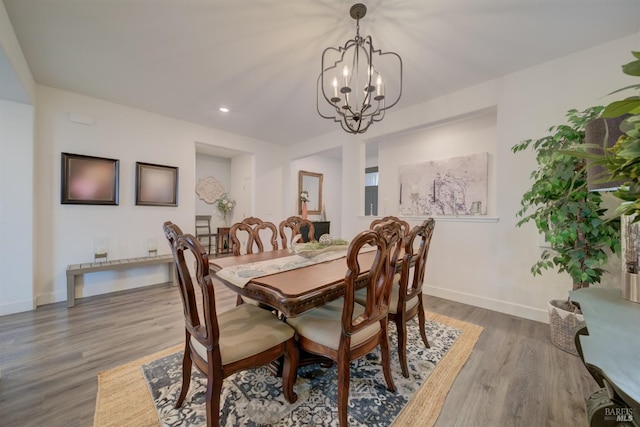 dining area with hardwood / wood-style floors and an inviting chandelier