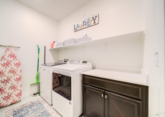 clothes washing area with cabinets, washer and dryer, and light tile patterned floors