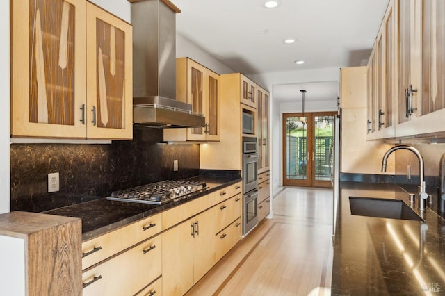 kitchen featuring range hood, stainless steel appliances, hanging light fixtures, glass insert cabinets, and light brown cabinets