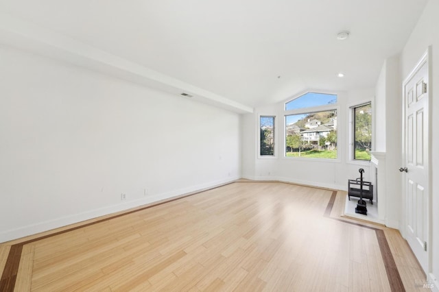 unfurnished living room with lofted ceiling, baseboards, visible vents, and light wood finished floors