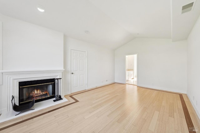 unfurnished living room featuring baseboards, visible vents, a glass covered fireplace, vaulted ceiling, and light wood-style floors