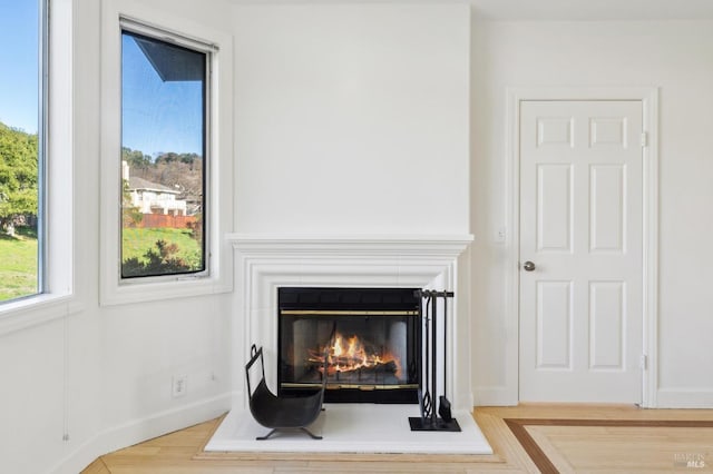 details with wood finished floors, a glass covered fireplace, and baseboards