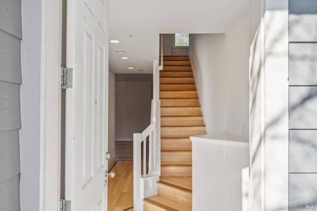 stairway with wood finished floors and recessed lighting