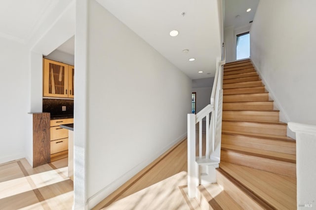 stairway featuring baseboards, wood finished floors, and recessed lighting