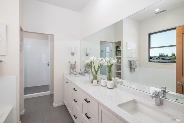 bathroom featuring tile patterned floors, vanity, and a tile shower