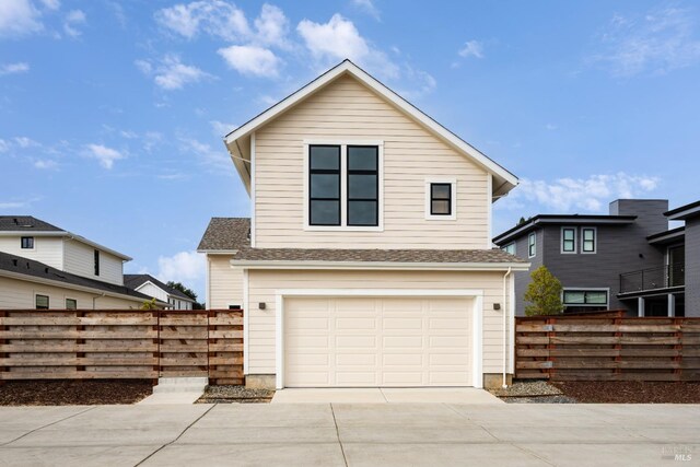 traditional-style house with an attached garage, fence, and concrete driveway