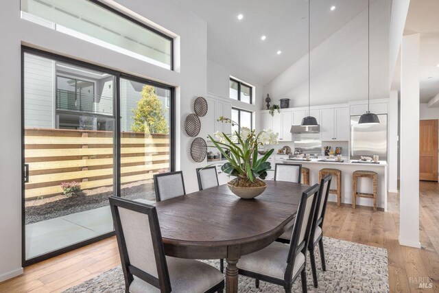 dining room featuring high vaulted ceiling, recessed lighting, and light wood-style flooring