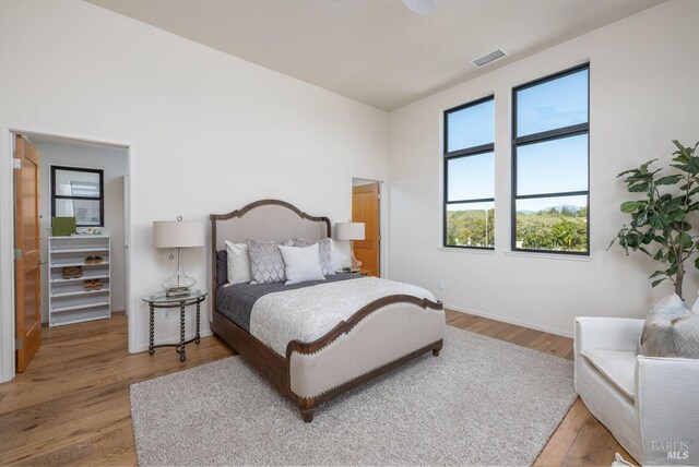bedroom featuring baseboards, wood finished floors, and visible vents