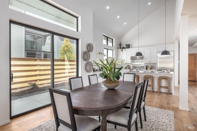 dining room with high vaulted ceiling and light wood-type flooring