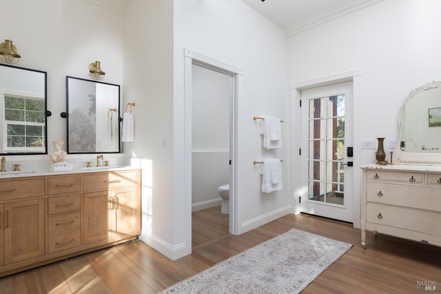 bathroom with hardwood / wood-style floors, vanity, toilet, and ornamental molding