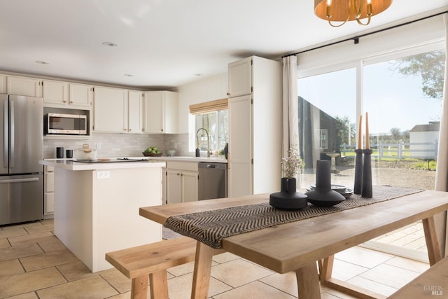 kitchen featuring sink, stainless steel appliances, light tile patterned floors, backsplash, and white cabinets