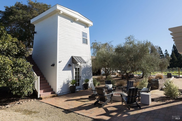 rear view of property with a patio area and an outdoor fire pit