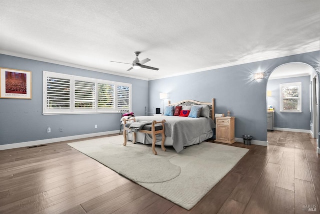 bedroom with ceiling fan, hardwood / wood-style floors, ornamental molding, and a textured ceiling