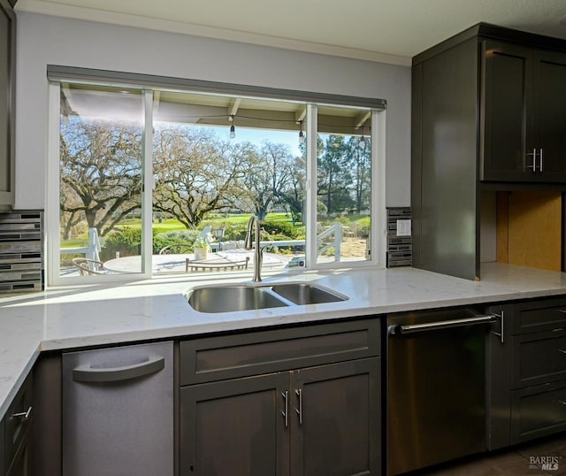 kitchen with stainless steel dishwasher, dark brown cabinets, sink, and light stone counters