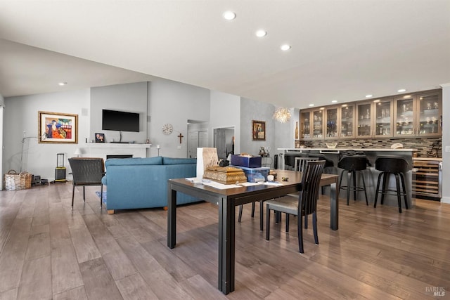 dining space with vaulted ceiling, beverage cooler, and wood-type flooring