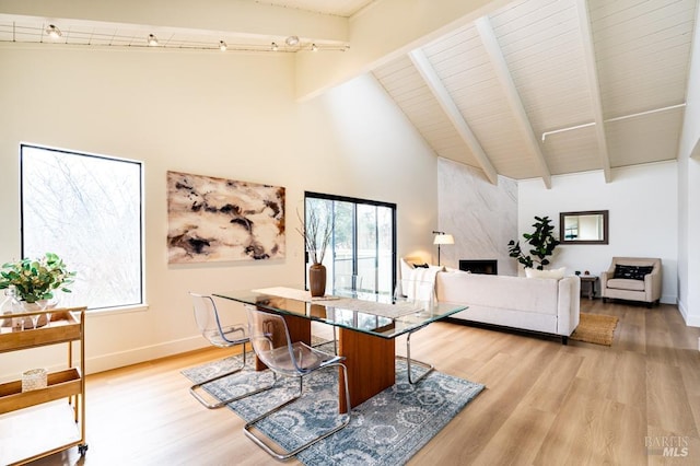 living room with beamed ceiling, light wood-type flooring, high vaulted ceiling, and plenty of natural light