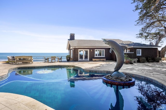 view of swimming pool featuring french doors, a water view, and a patio area