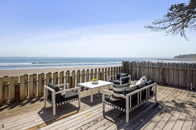 deck with outdoor lounge area, a water view, and a beach view