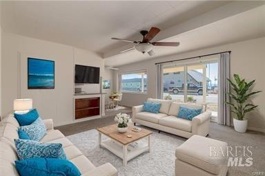 living room featuring carpet flooring, ceiling fan, and a wealth of natural light