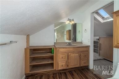 bathroom featuring vaulted ceiling with skylight and vanity