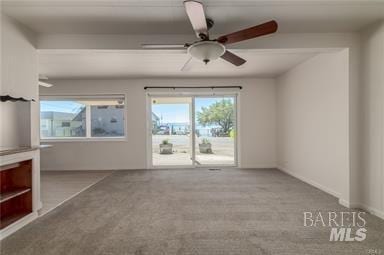 carpeted empty room with ceiling fan and a healthy amount of sunlight