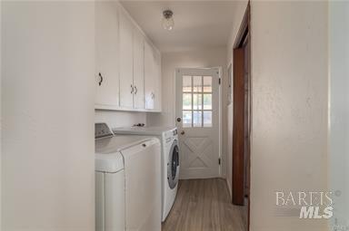 laundry room with washer and dryer, cabinets, and light wood-type flooring