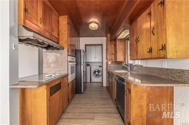 kitchen with black appliances, washer / dryer, light wood-type flooring, and sink