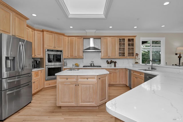 kitchen featuring ornamental molding, stainless steel appliances, sink, wall chimney range hood, and an island with sink