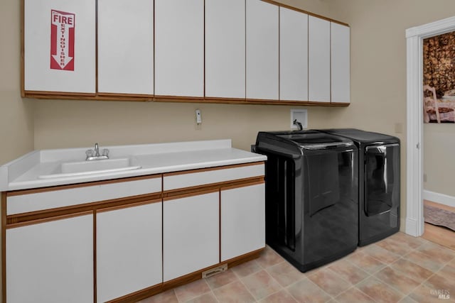 clothes washing area featuring cabinets, sink, and washing machine and dryer