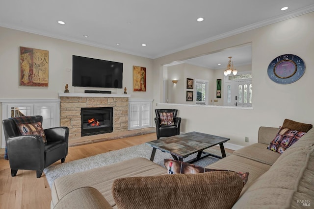 living room with a stone fireplace, ornamental molding, and light wood-type flooring