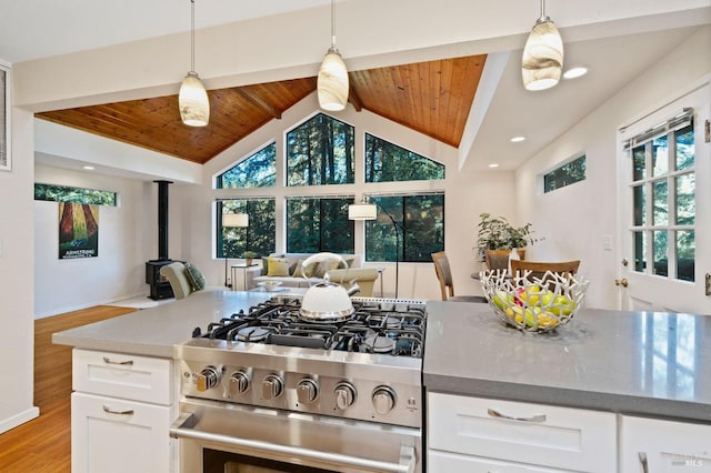 kitchen with lofted ceiling, open floor plan, gas range, wood ceiling, and a wood stove