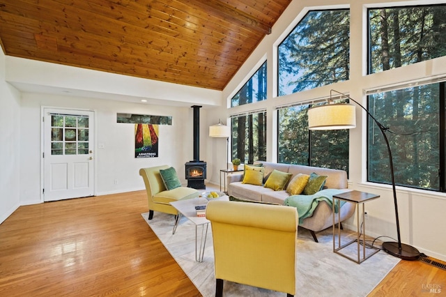 sunroom featuring lofted ceiling with beams, a wood stove, and wood ceiling