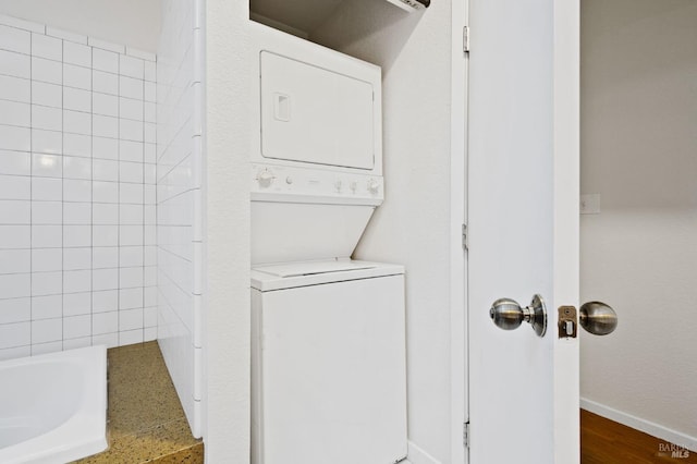 laundry room with baseboards and stacked washing maching and dryer
