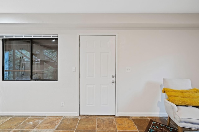 foyer featuring baseboards and stone tile flooring