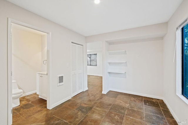 empty room with visible vents, stone finish floor, and baseboards
