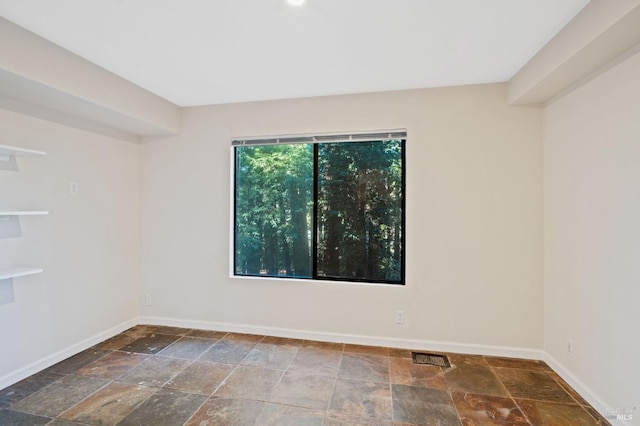 empty room featuring baseboards and stone finish flooring