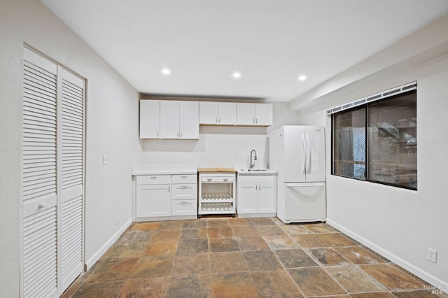 kitchen with white cabinetry, sink, and white refrigerator