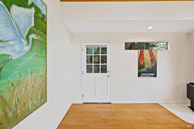 doorway to outside featuring a wood stove, recessed lighting, baseboards, and light wood-type flooring