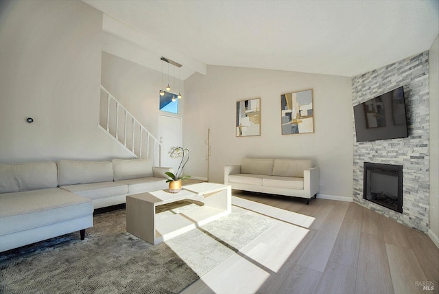 living room featuring a stone fireplace, wood-type flooring, and vaulted ceiling