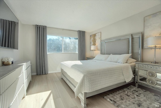 bedroom with a textured ceiling and light hardwood / wood-style flooring