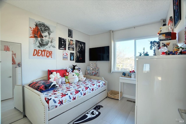 bedroom with a textured ceiling and light hardwood / wood-style flooring