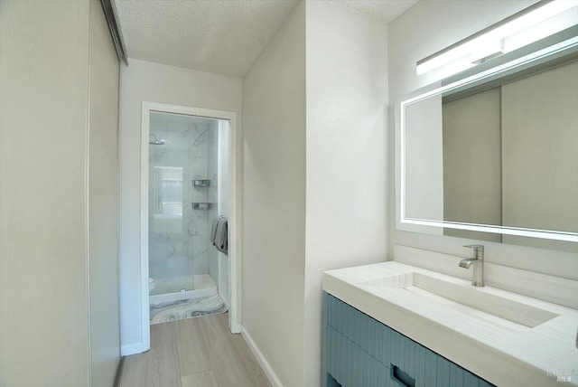 bathroom featuring vanity, a tile shower, and a textured ceiling