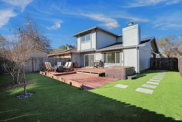 back of house with a lawn, a wooden deck, and a hot tub